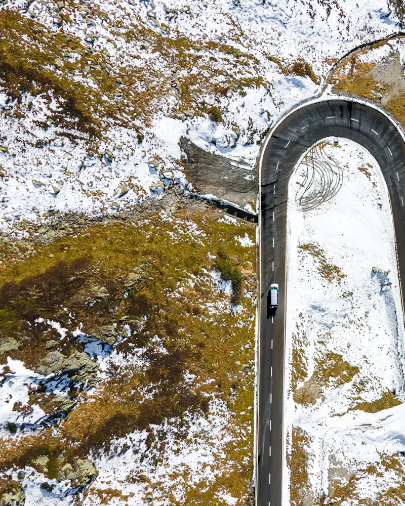 A hairpin road cut into snowy rock, from above