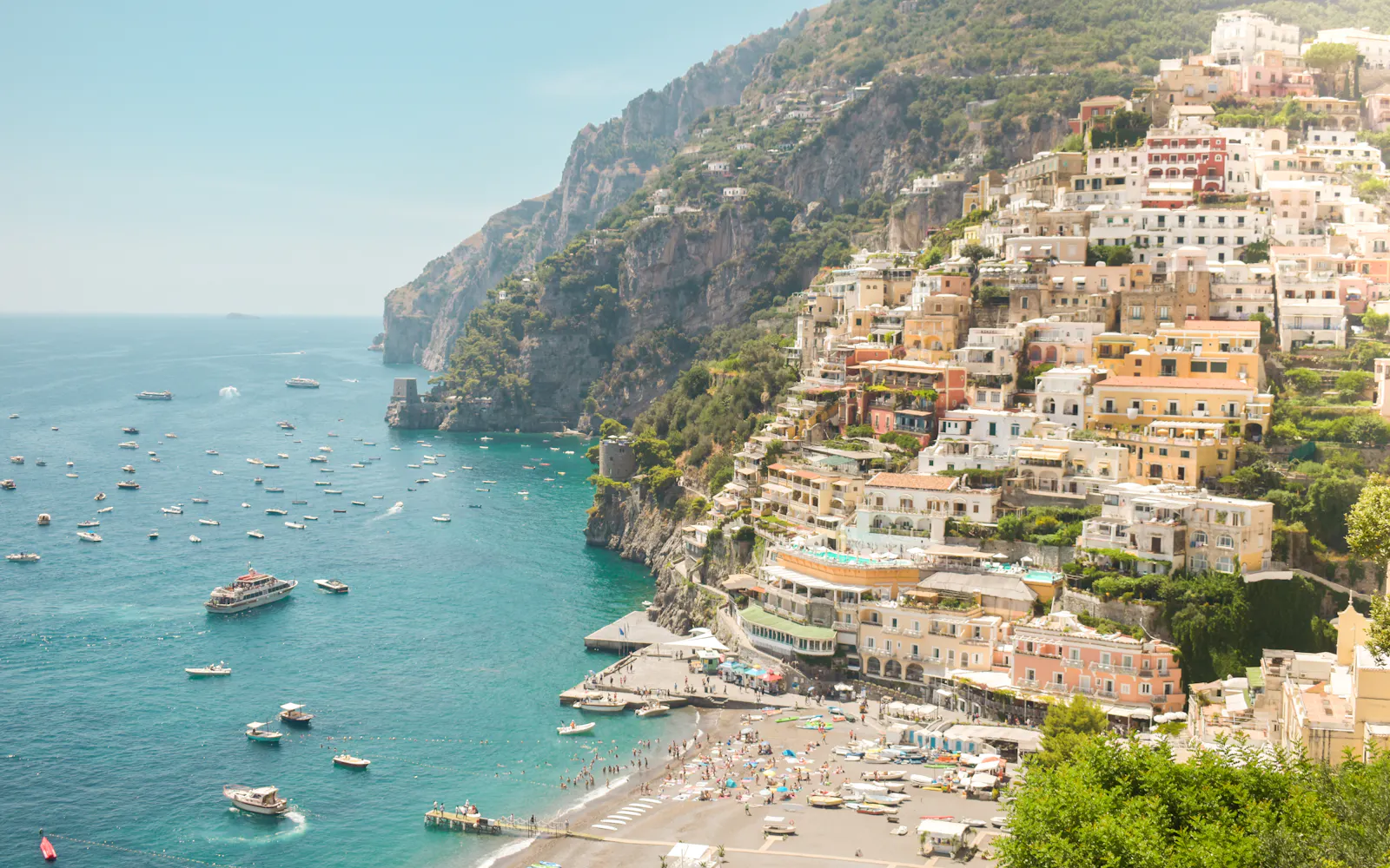 Positano's houses climbing a green cliff above a turquoise bay
