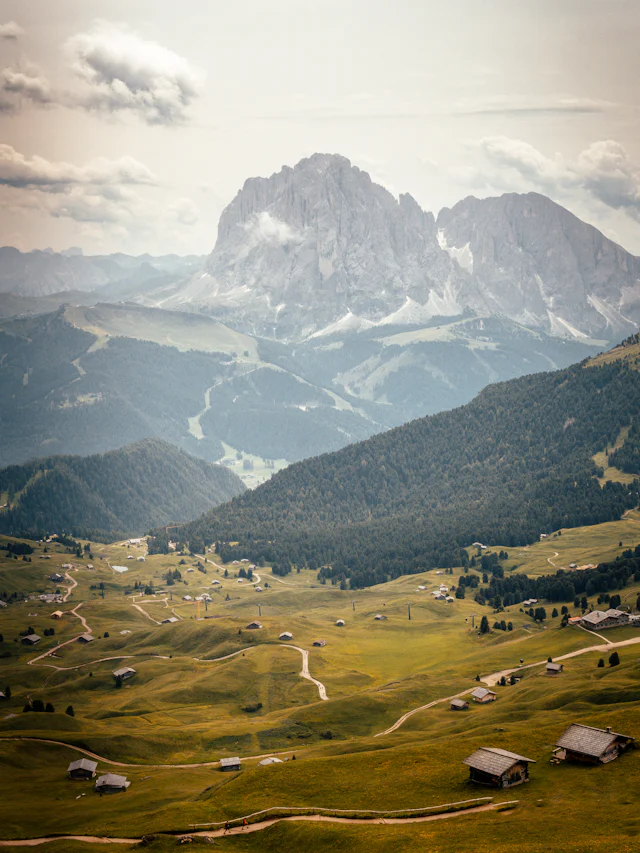 Pale Dolomite peaks above a green valley of meadows and farmhouses