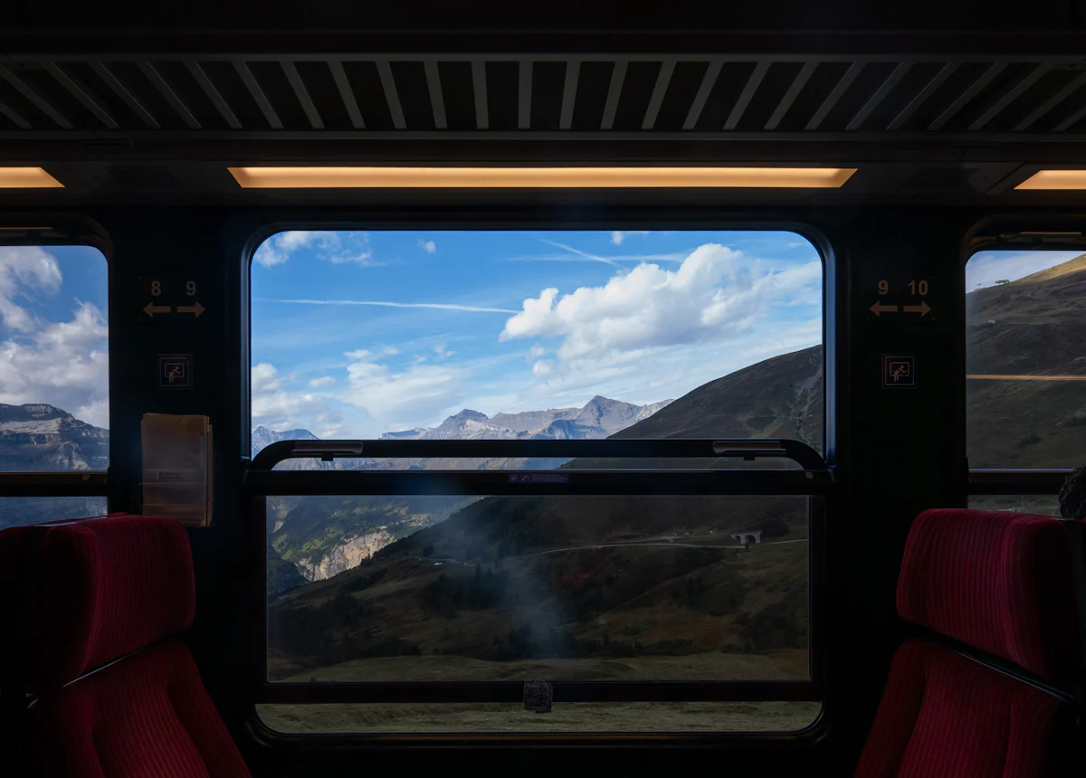 Mountains framed by a train window and red seats