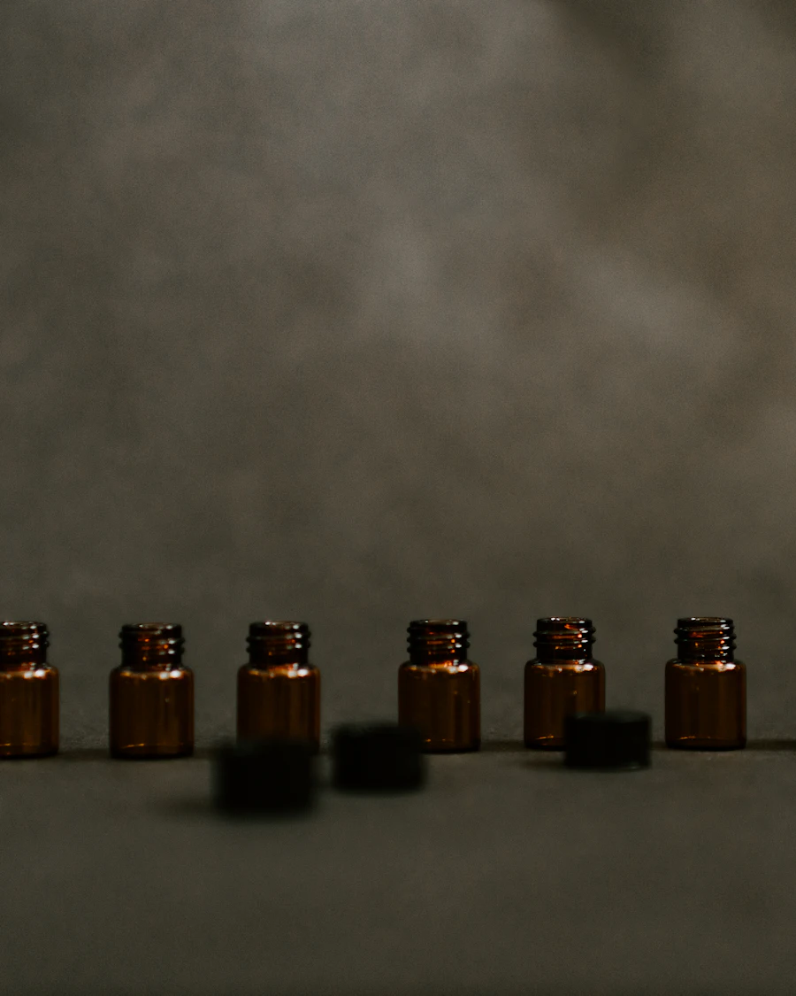 A row of small amber glass bottles on a stone ledge